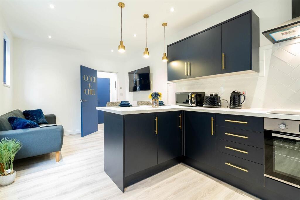 Modern open-plan kitchen with navy cabinetry, b...