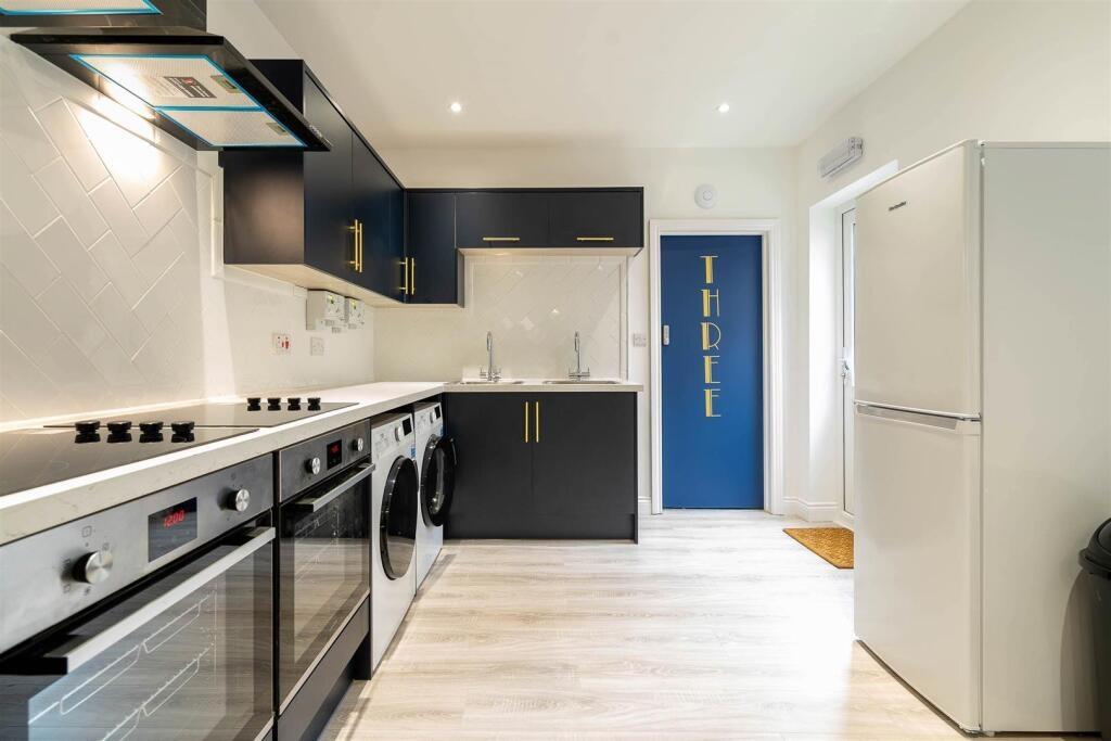 Modern fully fitted kitchen with sleek dark cab...