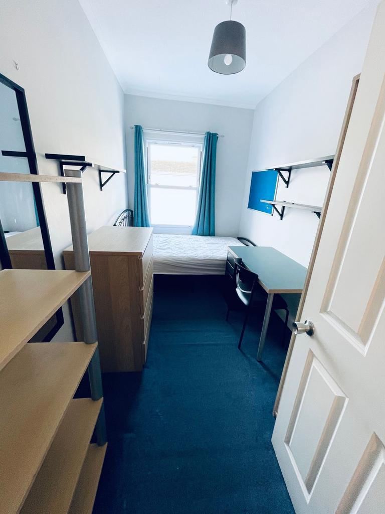 Bright, neatly furnished single bedroom with a ...