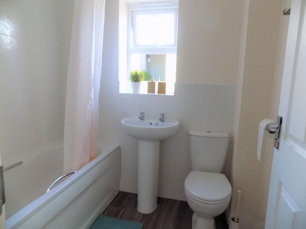Bright, tidy bathroom with a bath and shower cu...