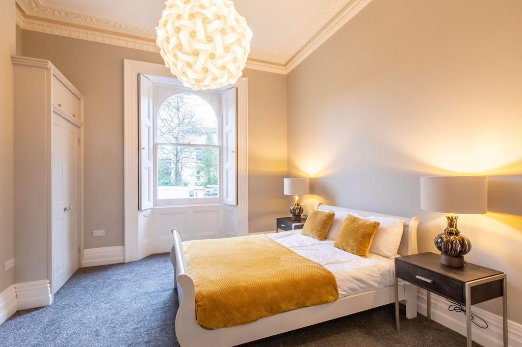 Bright, stylish bedroom with a large arched sas...