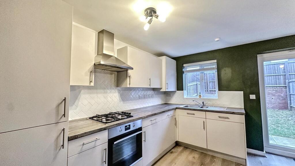 Modern fitted kitchen with white cabinets, buil...