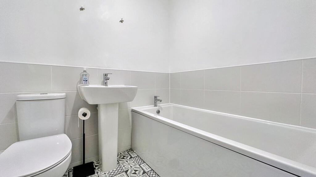 Bright, modern bathroom with a white bathtub, p...