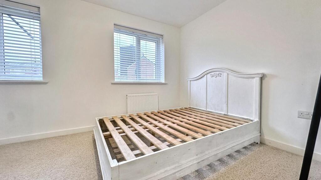 Bright, neutral double bedroom with a white woo...