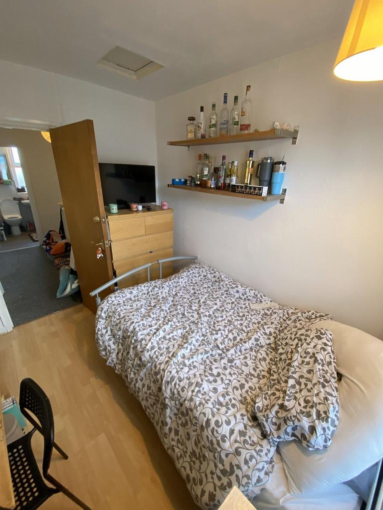 Tidy single bedroom with patterned bedding, a m...