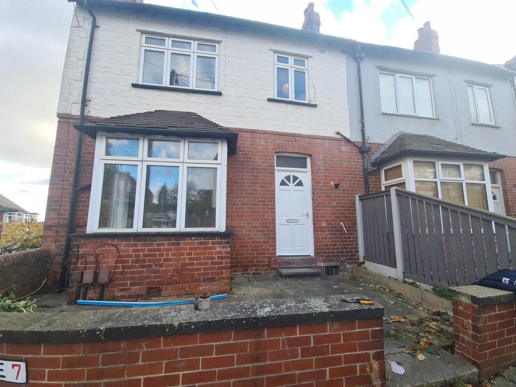 Red-brick terraced house with bay window, paved...