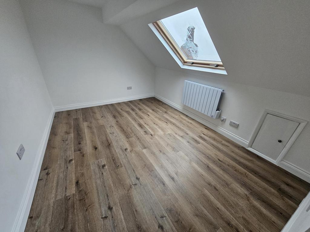Bright loft bedroom with angled ceiling, wood-e...
