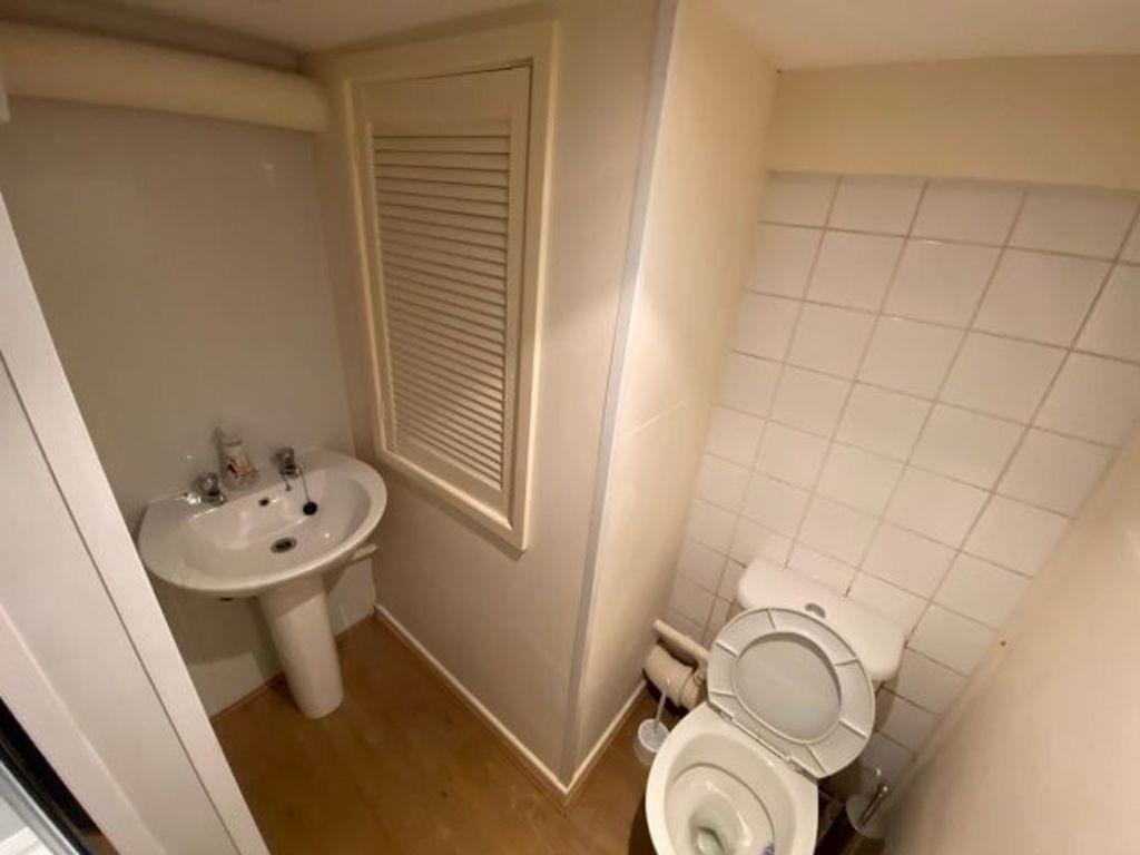 Compact bathroom with pedestal sink, tiled wall...