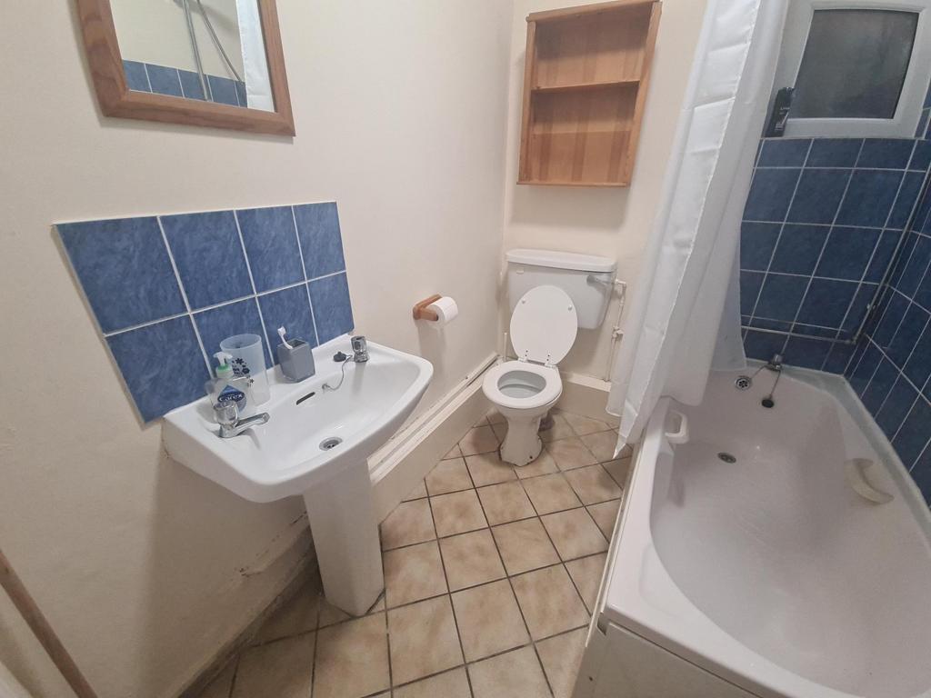 Clean, neutrally tiled bathroom featuring a bat...