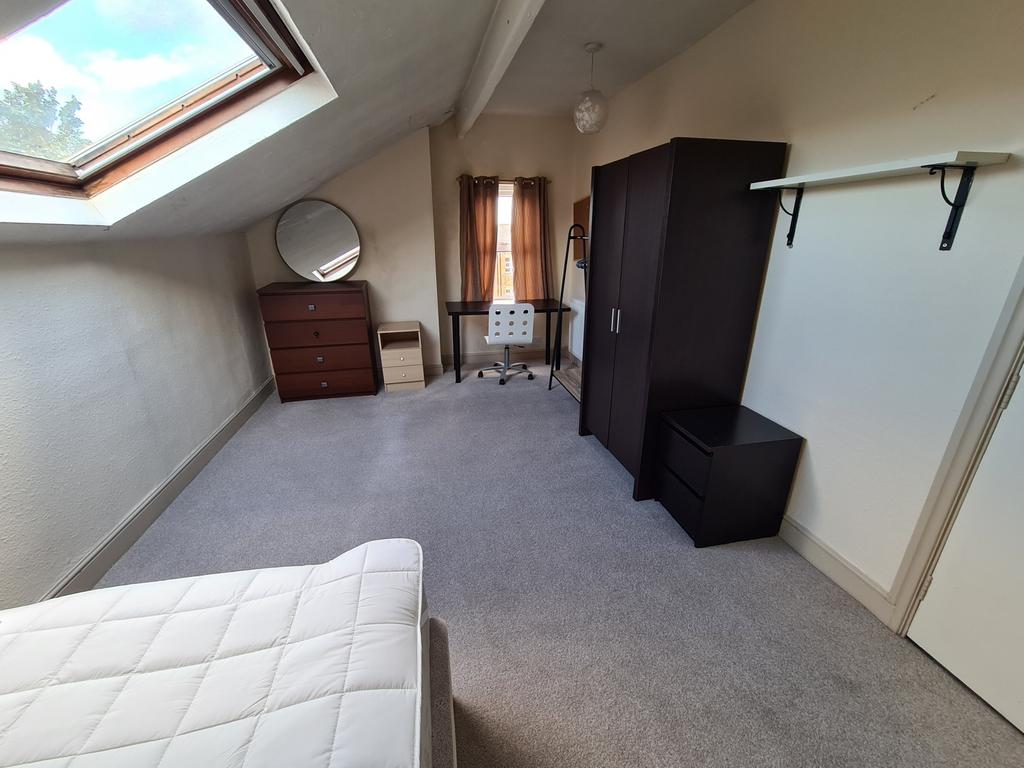 A cozy double bedroom featuring a sloped ceilin...