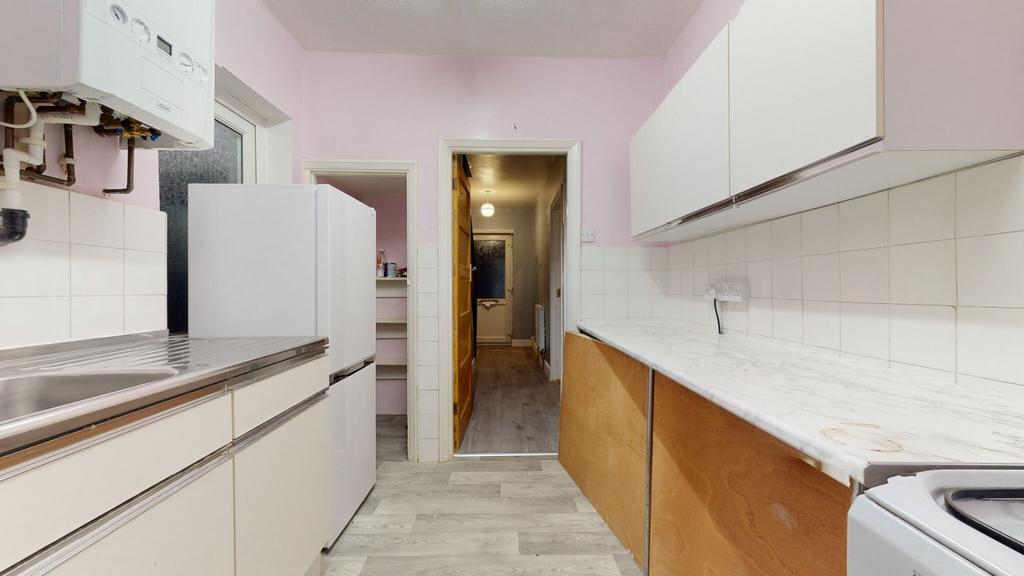 Bright galley kitchen with white cabinetry, til...