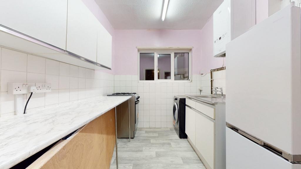 Bright galley kitchen with light countertops, i...
