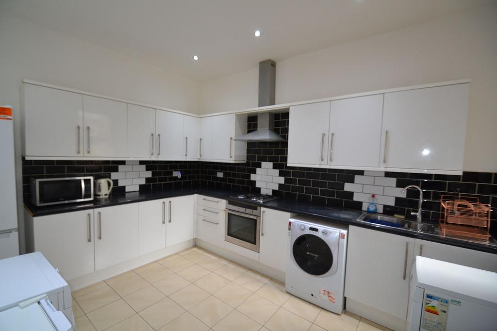 Modern kitchen featuring sleek white cabinets, ...