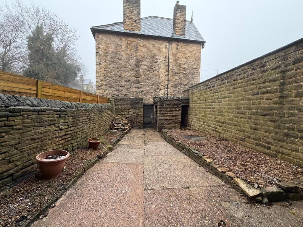 Private walled yard with paved pathway, raised ...