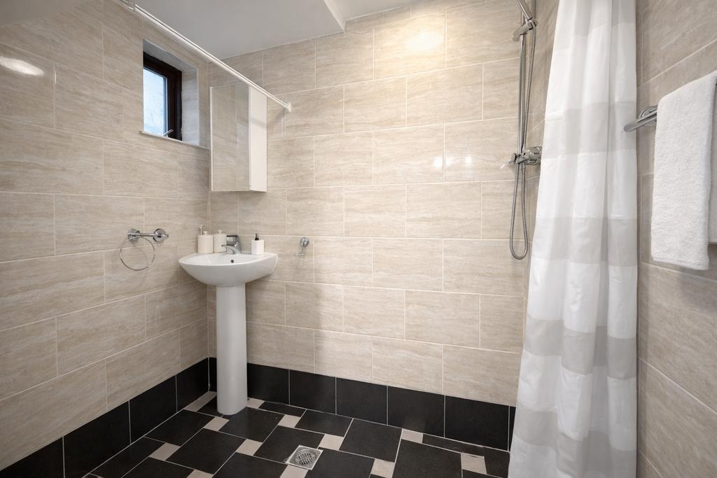 Modern tiled bathroom with a pedestal sink, mir...
