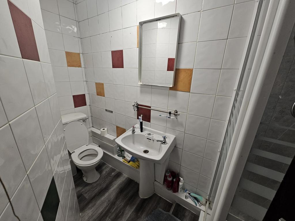 Clean tiled bathroom with a pedestal sink, mirr...