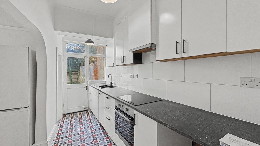 Bright, modern galley kitchen with white cabine...