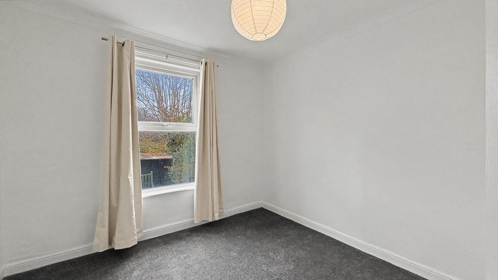 Bright, freshly painted bedroom with a large wi...