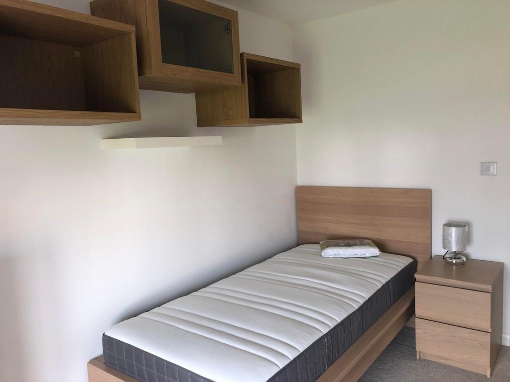 A tidy and well-lit single bedroom with modern ...