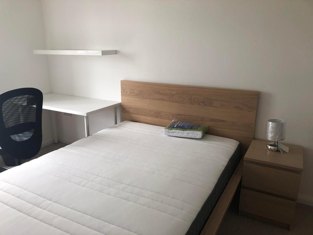 A bright and tidy double bedroom featuring mode...