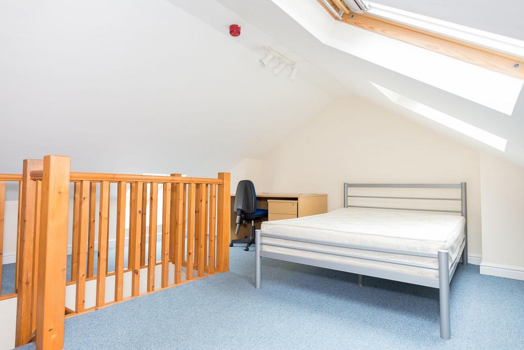 Bright attic double bedroom with a metal bed fr...