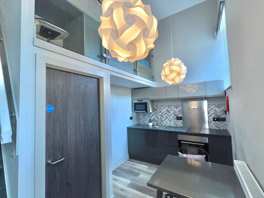 Modern kitchenette with dark gloss cabinets, bu...