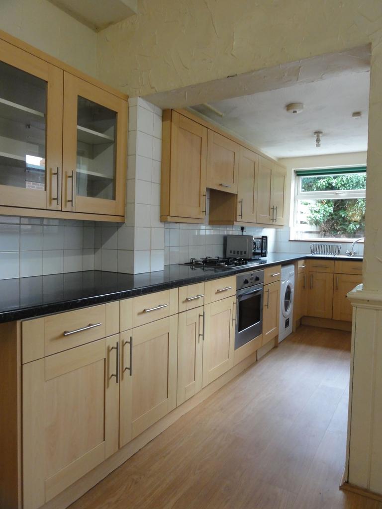 Bright galley kitchen with light wood cabinets,...