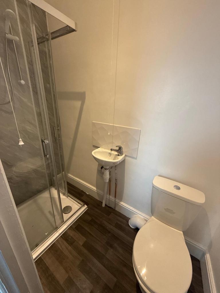 Compact modern bathroom with corner shower encl...