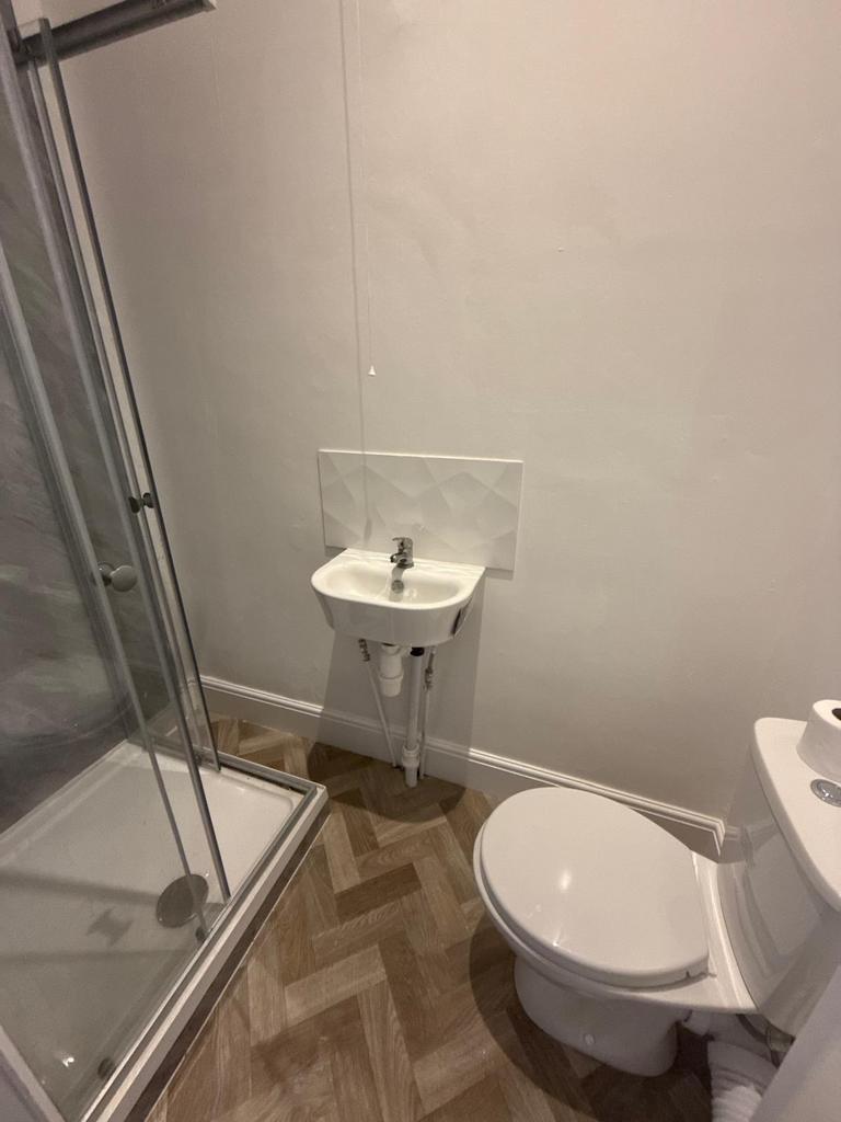 Compact modern bathroom with a corner shower cu...