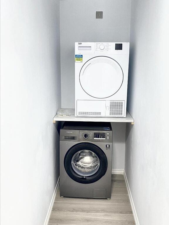 Neat built-in laundry alcove with stacked washe...