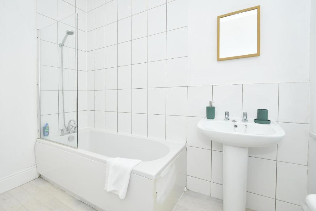 Bright white bathroom with a bathtub and shower...