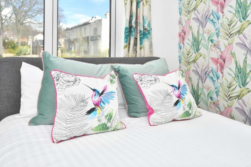 Bright, neatly made bedroom with patterned cush...