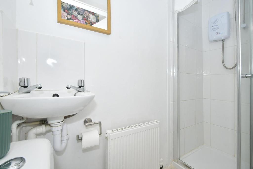 Bright white bathroom with a corner shower, ped...