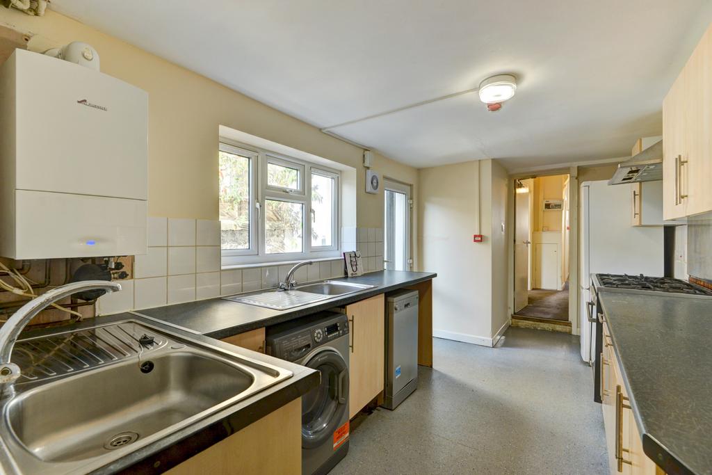 Bright galley kitchen with large window, dual s...