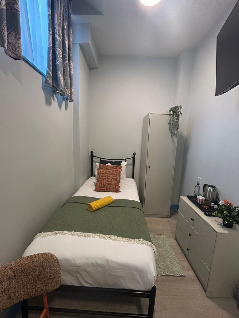 Bright, neatly arranged single bedroom with a c...