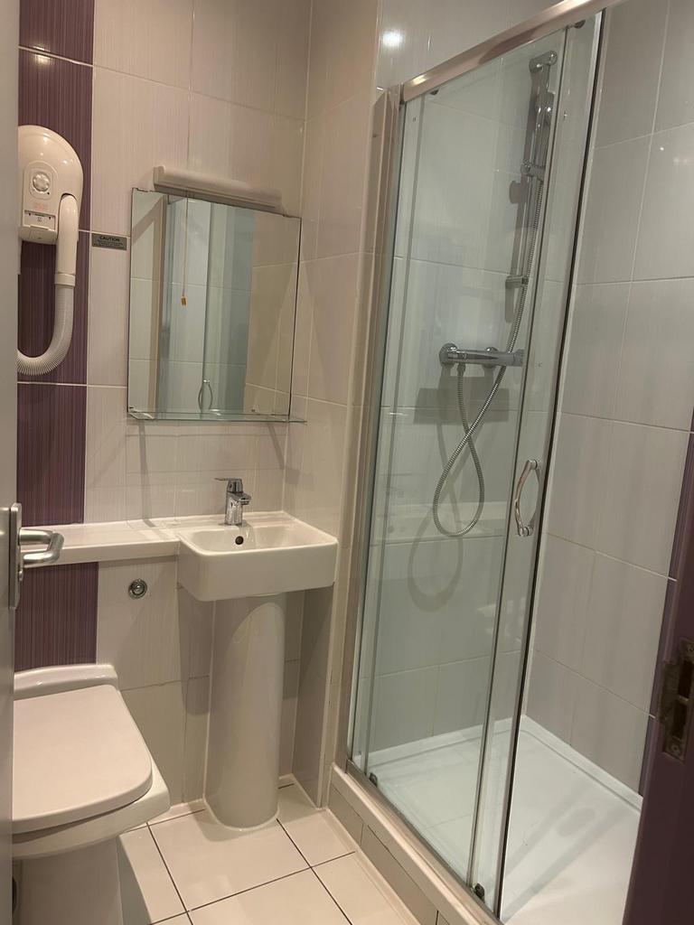 Bright, modern tiled bathroom with a glass-encl...