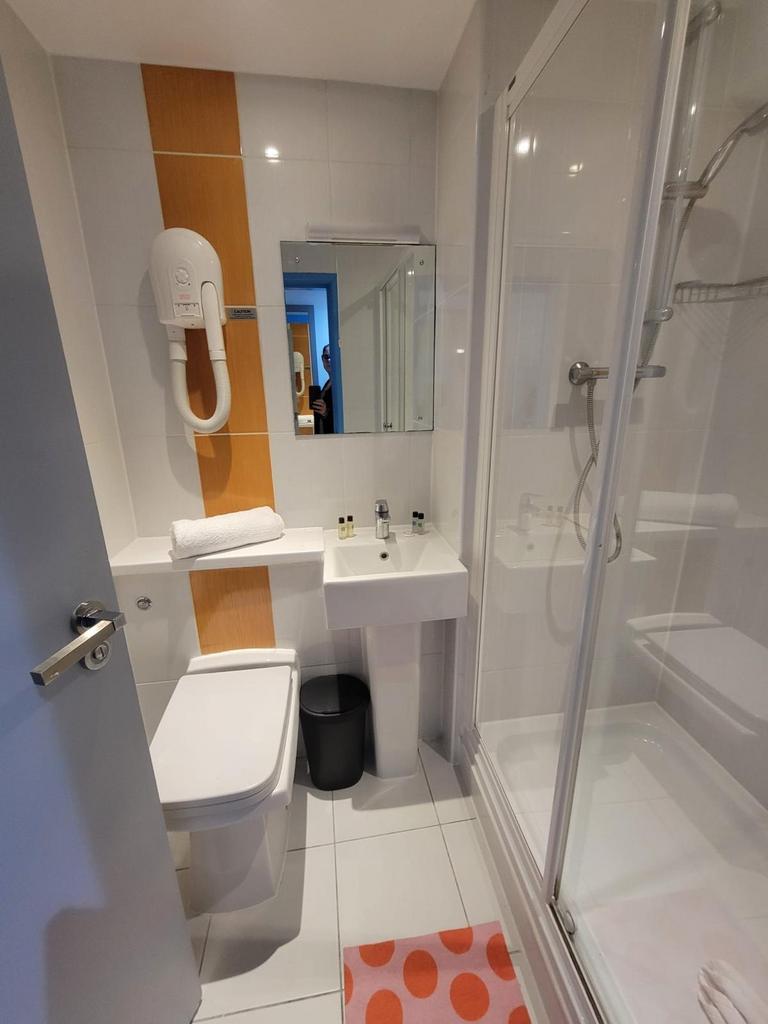 Bright, modern bathroom with white tiles, a gla...