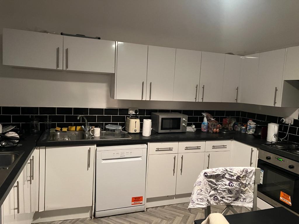 Modern fitted kitchen with white cabinetry, bla...