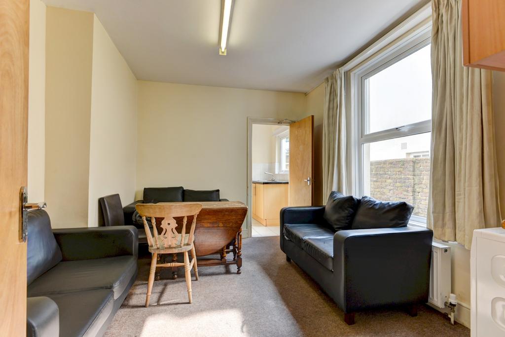 Bright communal lounge with two sofas, a dining...