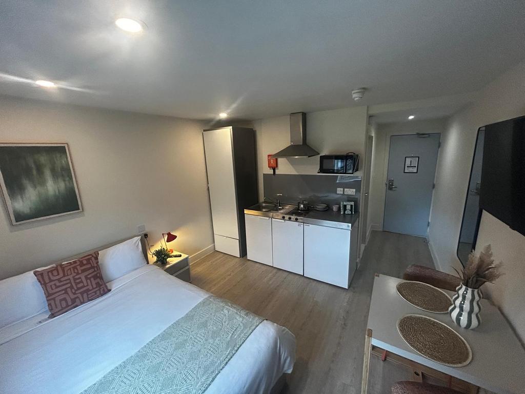 Bright, modern studio with a neatly made double...