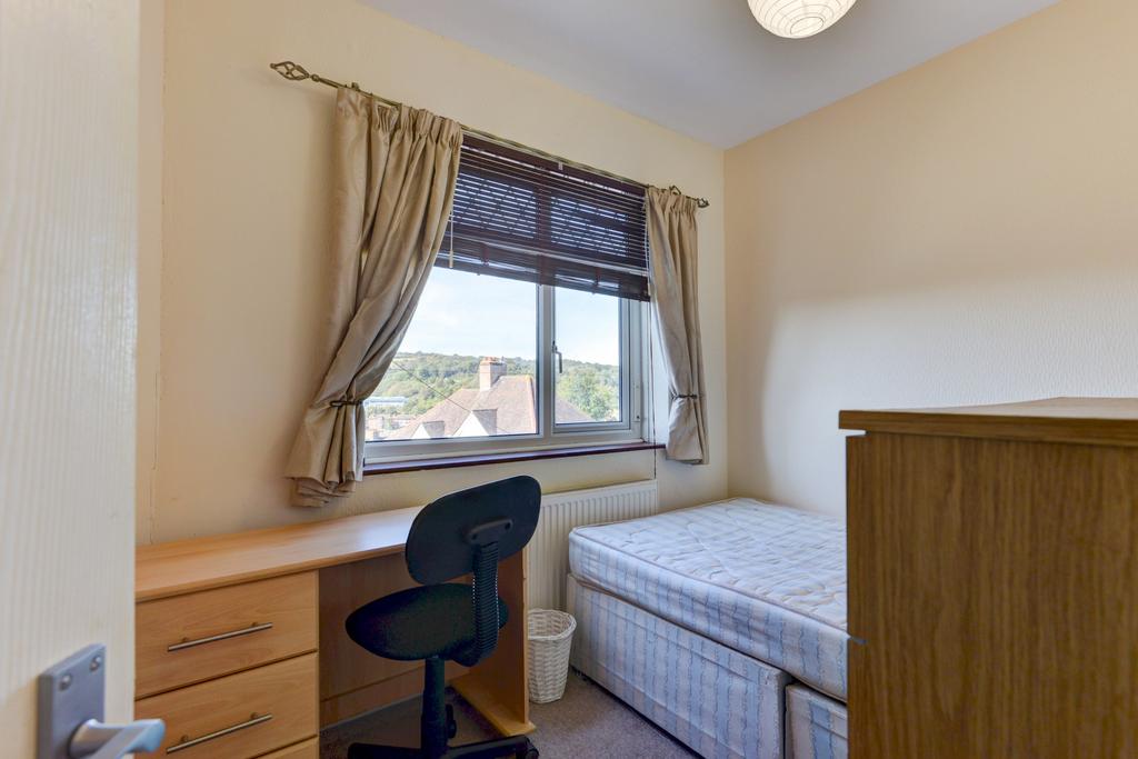 A cozy single bedroom featuring a neatly made b...