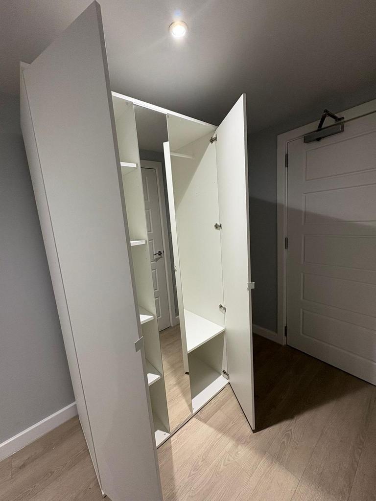 A clean, modern hallway with a tall white wardr...