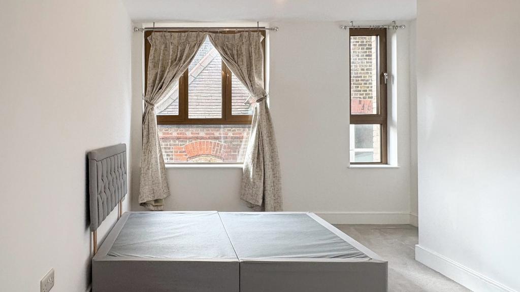 Bright, neutrally decorated bedroom with large ...