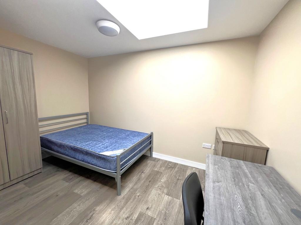 Bright, simply furnished bedroom with a double ...