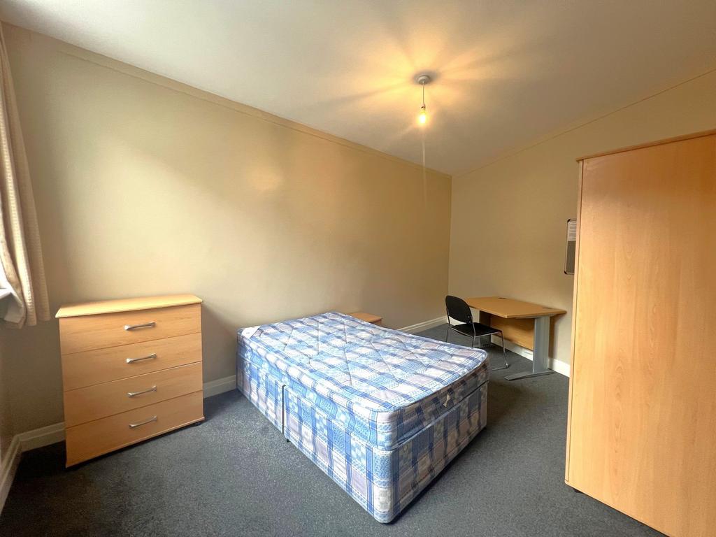 Bright, simply furnished bedroom with a double ...