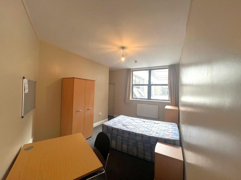 Bright single bedroom with a large window, fitt...