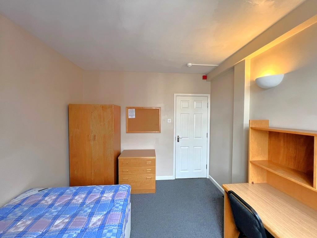 A well-organized bedroom with wooden furniture ...