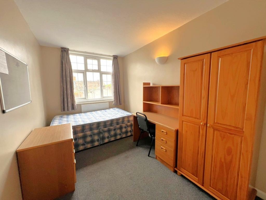 A cozy student bedroom featuring a single bed, ...