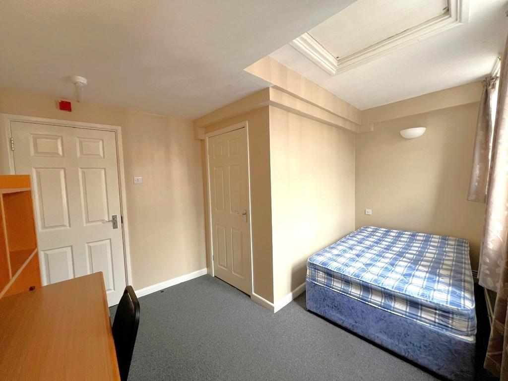 A modest bedroom with a single bed, a small des...