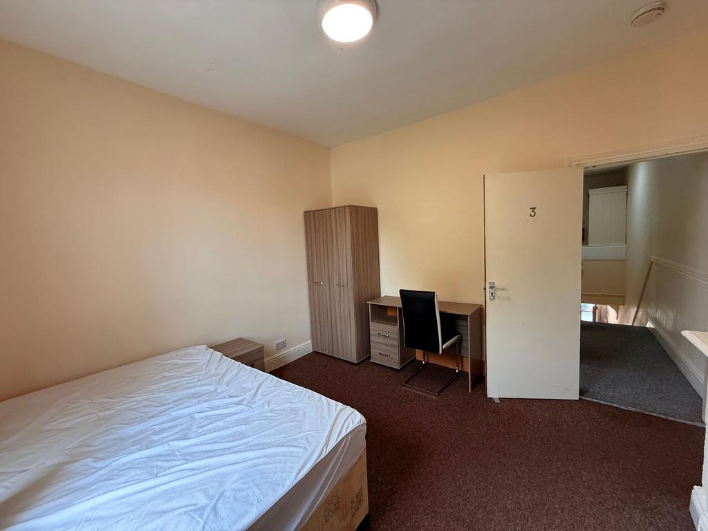 Bright, simply furnished bedroom with a double ...
